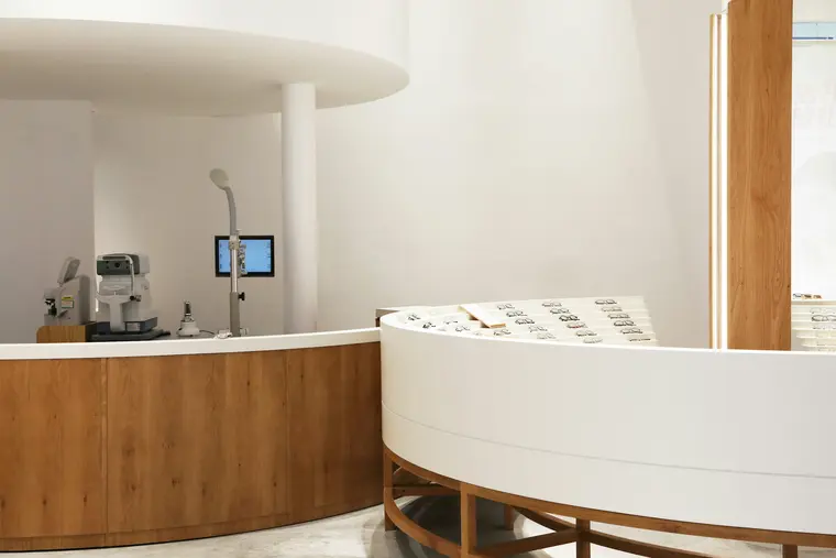 A shop counter built as one curve: an oak base under a white lacquered top, with a display run behind it.