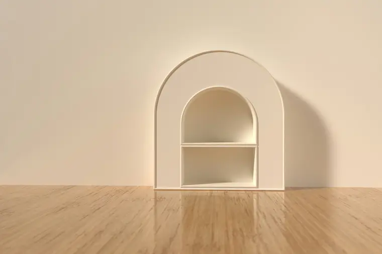 An arched niche formed in plaster on a cream wall, with a single shelf, above a pale timber floor.