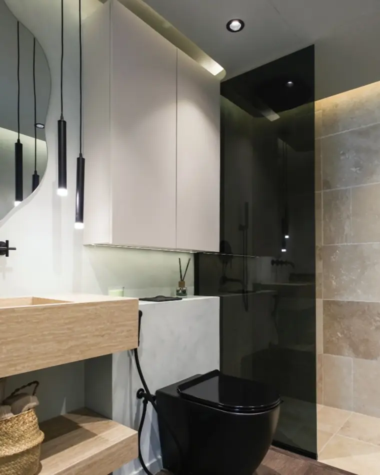 Bathroom in Downtown: travertine walls, a timber double vanity and round mirrors under pendants.