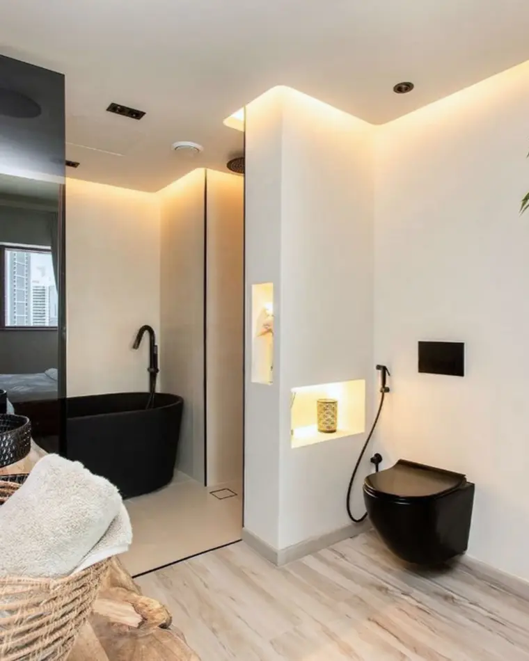 Bathroom in Business Bay: black freestanding bath behind a glass screen, a woven basket and an indoor tree.