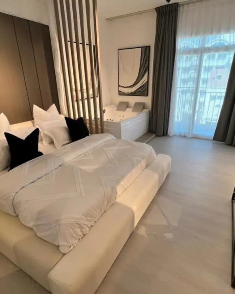 Bedroom in JVC: a bed with a slatted headboard, framed prints and dark accents.