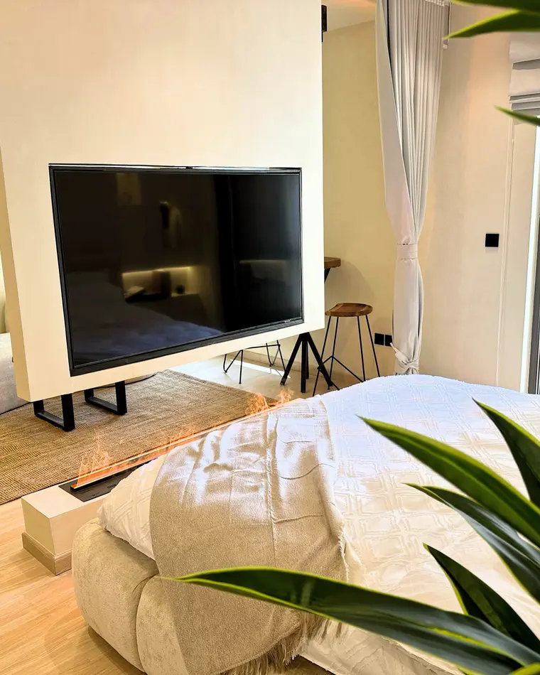 Bedroom in JBR: a bed facing a suspended media unit that divides the room.