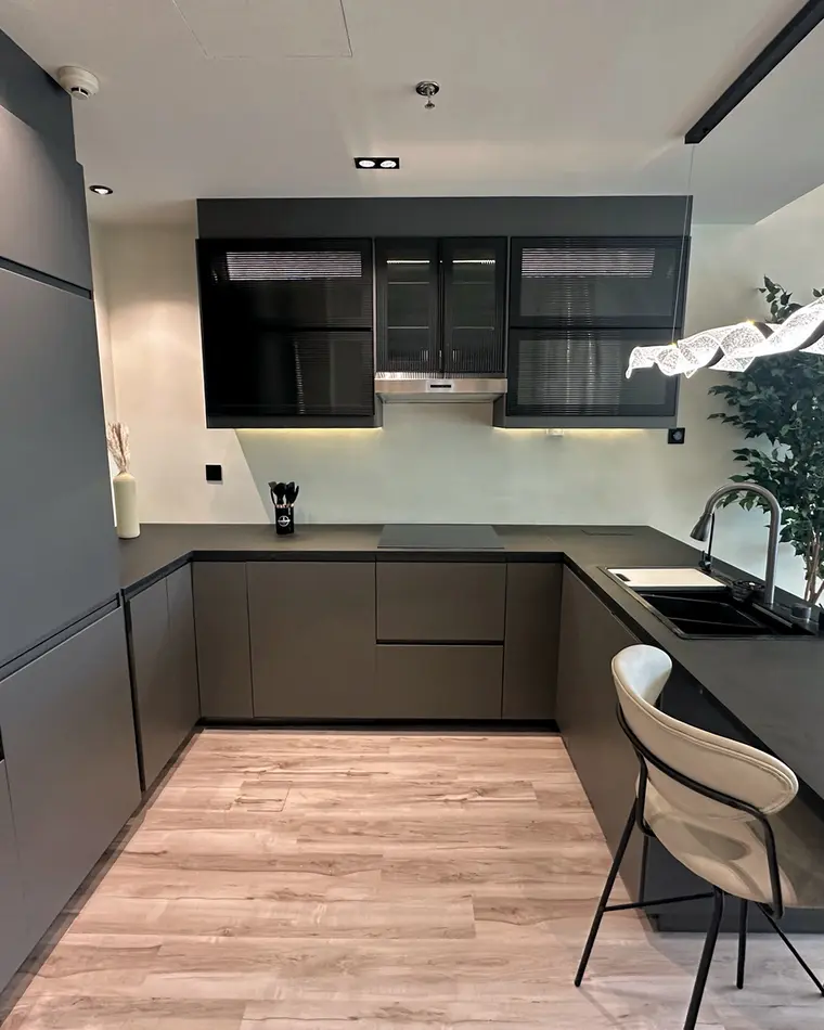 Kitchen in JLT: anthracite joinery to the ceiling, stone worktop, sculpted linear pendant.