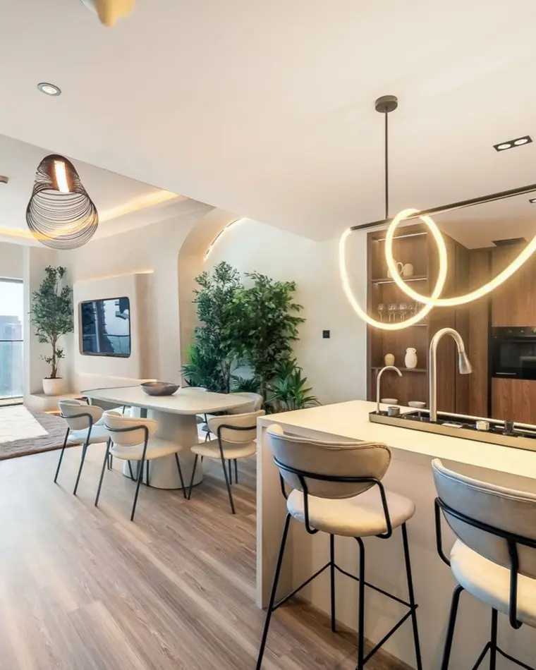 Kitchen in Dubai Marina: walnut joinery, a sculpted linear pendant and an island open onto the living space.