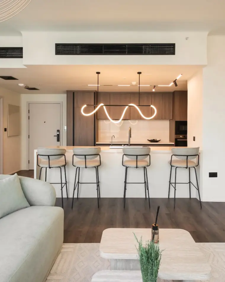 Kitchen in Downtown: island with bar stools, walnut joinery and a sculpted linear pendant.