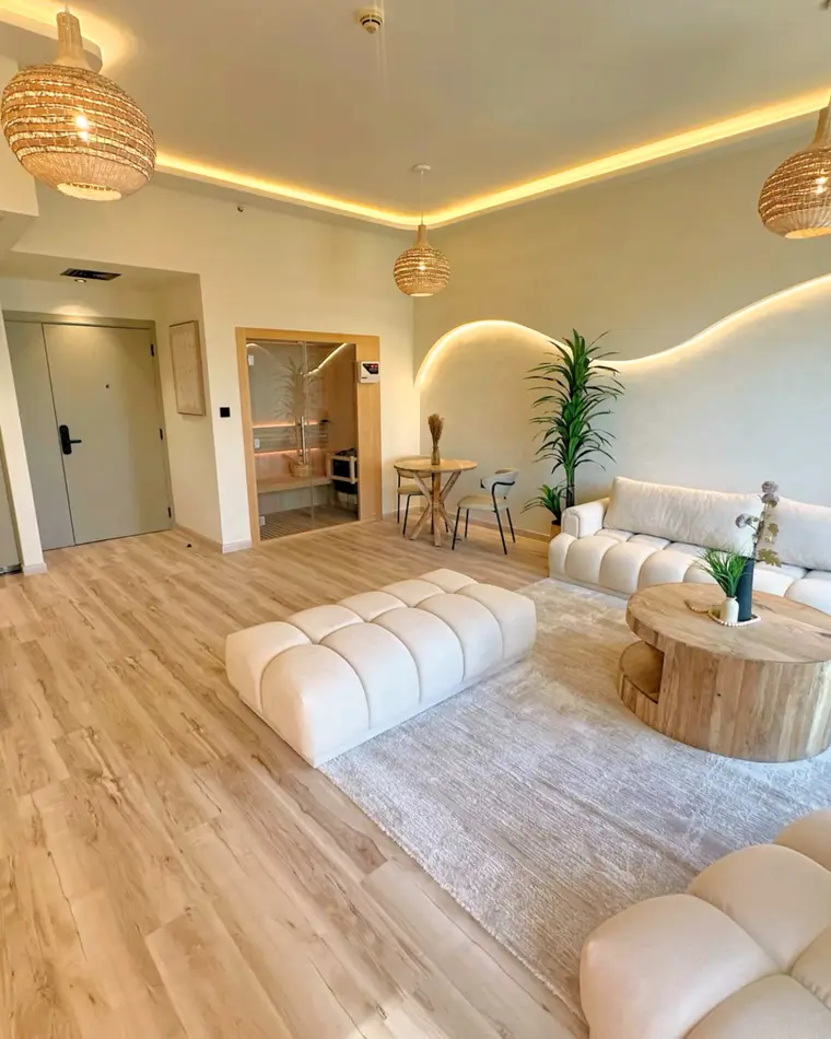 Living room in JBR: open living space with rattan pendants, boucle seating and a serpentine cove light.