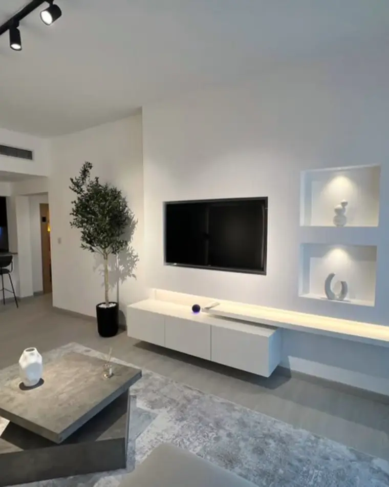 Living room in JVC: long boucle sofa, rattan pendants and a balcony onto the towers.